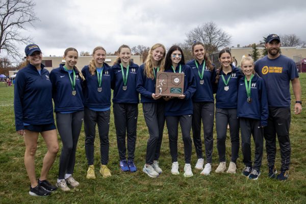 The girls cross country team and coaches pose for a photo with their Regional meet runner-up trophy Oct. 28.